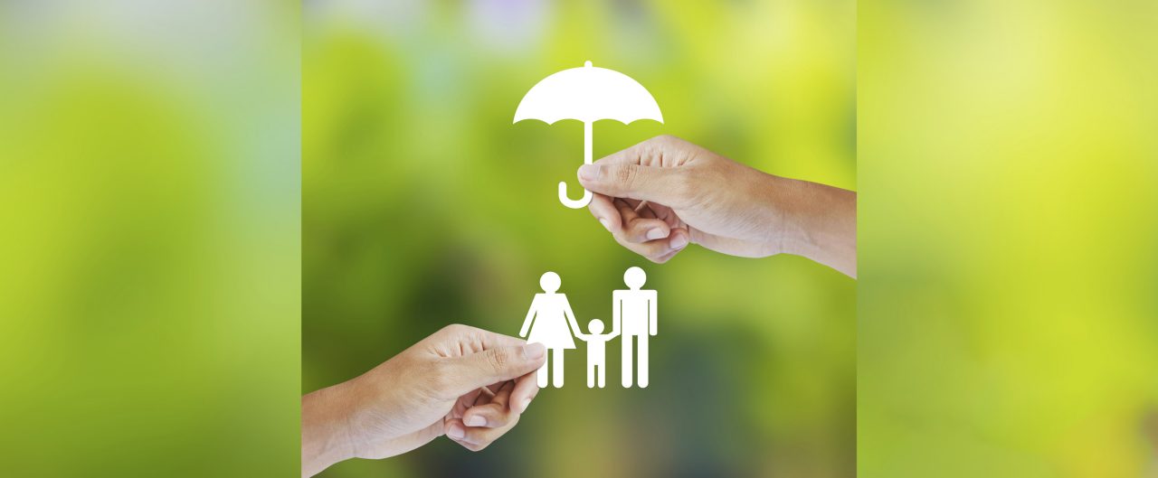 Hand holding a paper family and umbrella on green background