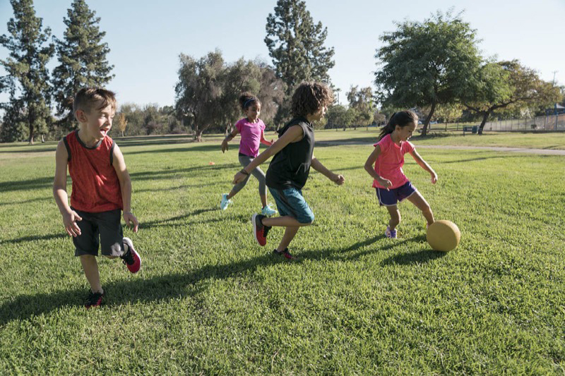 Several children player soccer together outside