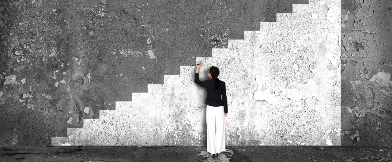 Businesswoman drawing ladder of success on a wall