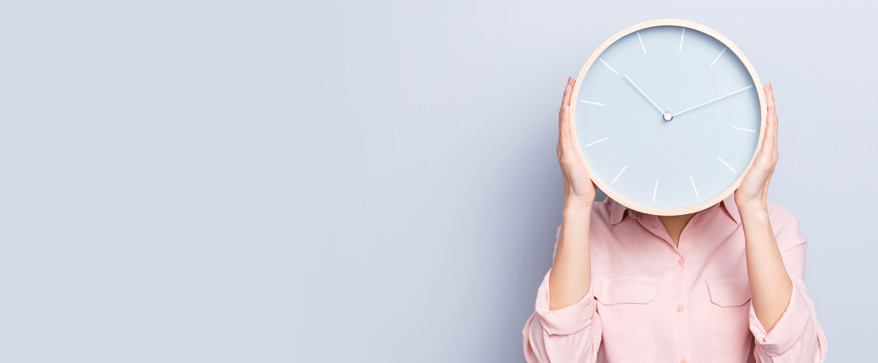 Woman holding a clock in front of her head.