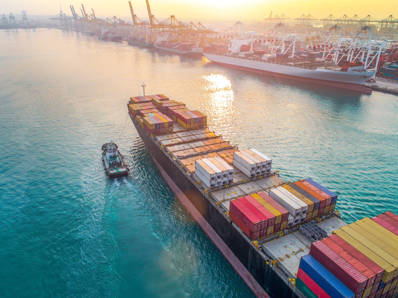 aerial view of colorful container ship vessels at sunset in clear blue water