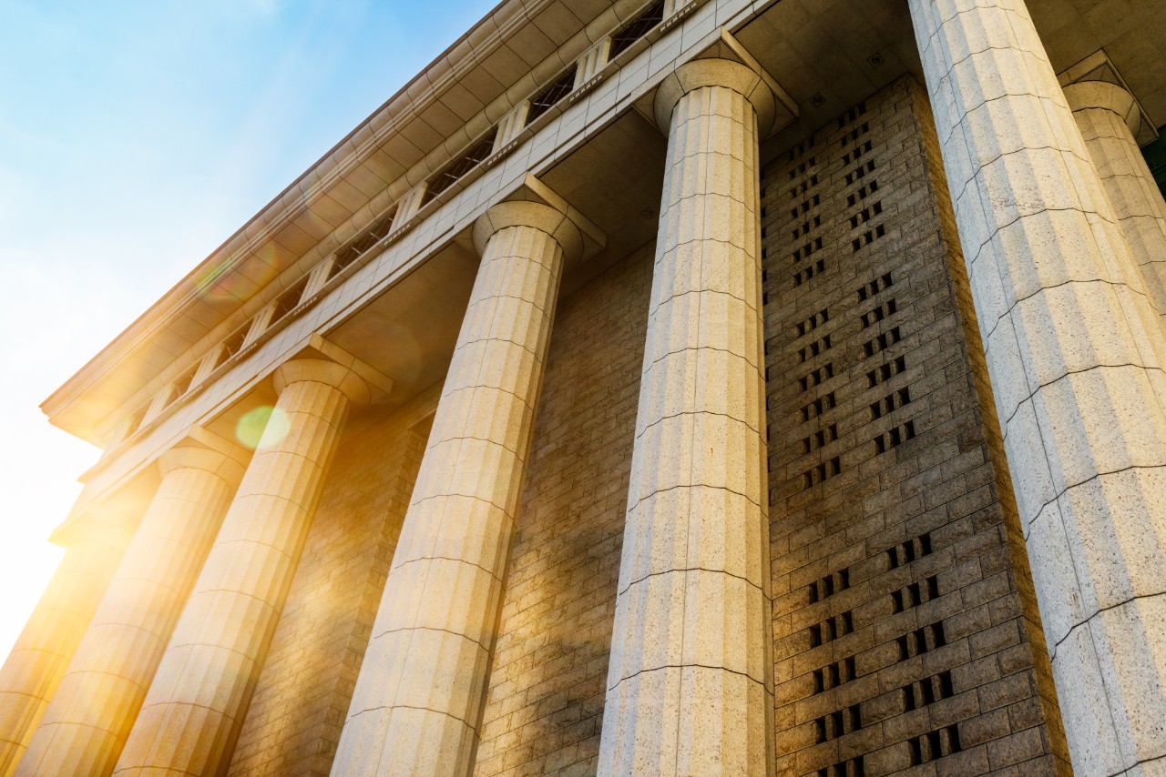 Grey marble column details on building with the sun shining coming from the left of the building