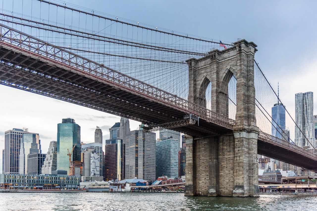 View over Lower Manhattan and the Brooklyn Bridge with the city skyline in the background and dark, cloudy sky