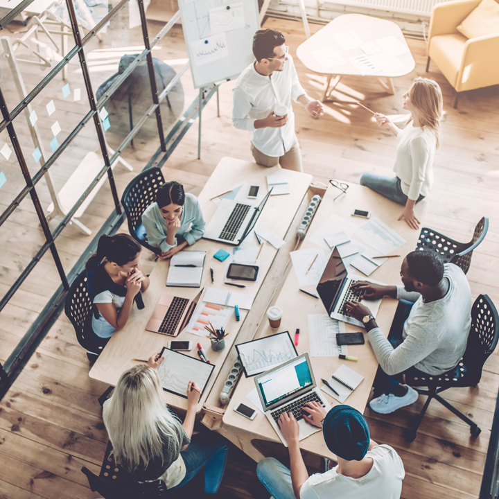 Top view of multiracial young creative people in modern office. Group of young business people are working together with laptop, tablet, smart phone, notebook. Successful hipster team in coworking.