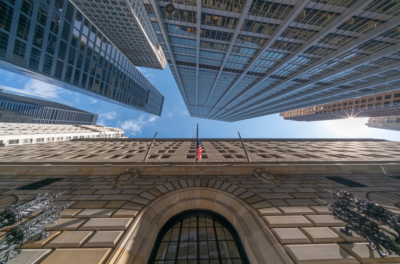 Close-up of the Federal Reserve building taken from down below with large gunmetal sconces and an American flag above the arched window