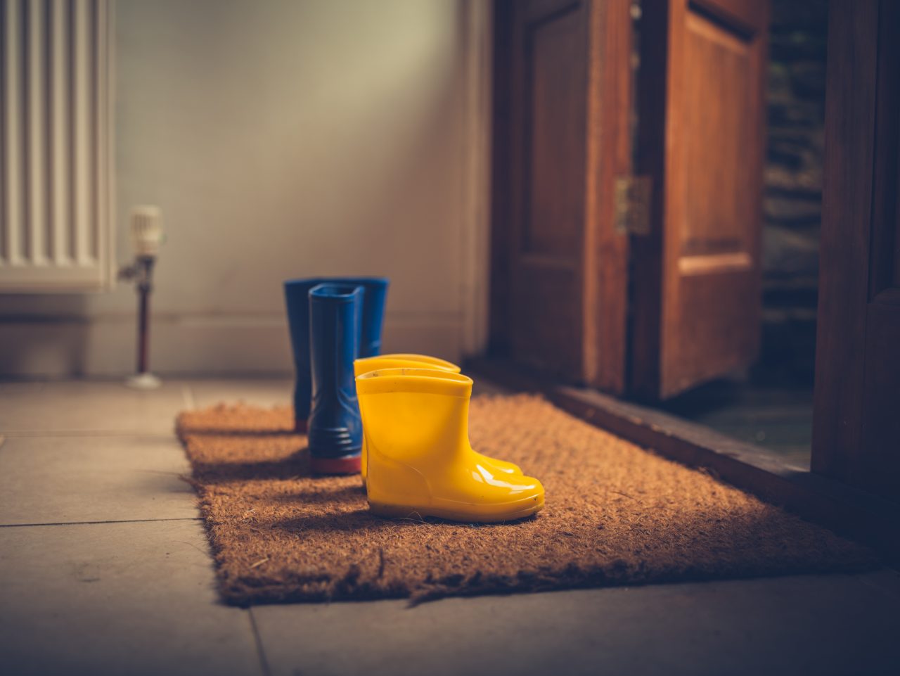 Two pairs of rubber rain boots by an open door