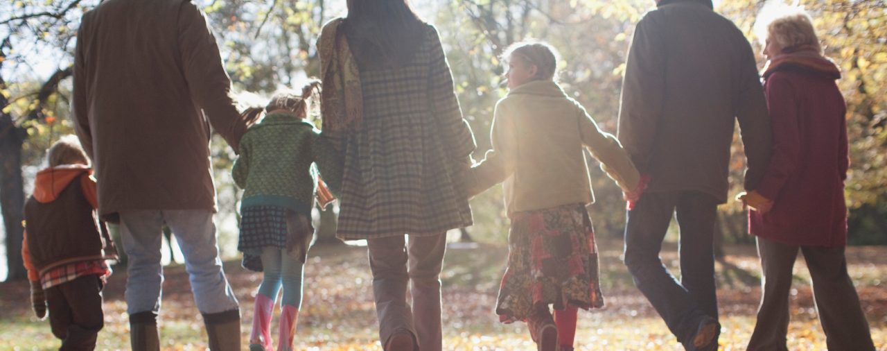 Parents and kids holding hands with autumn leaves surrounding them