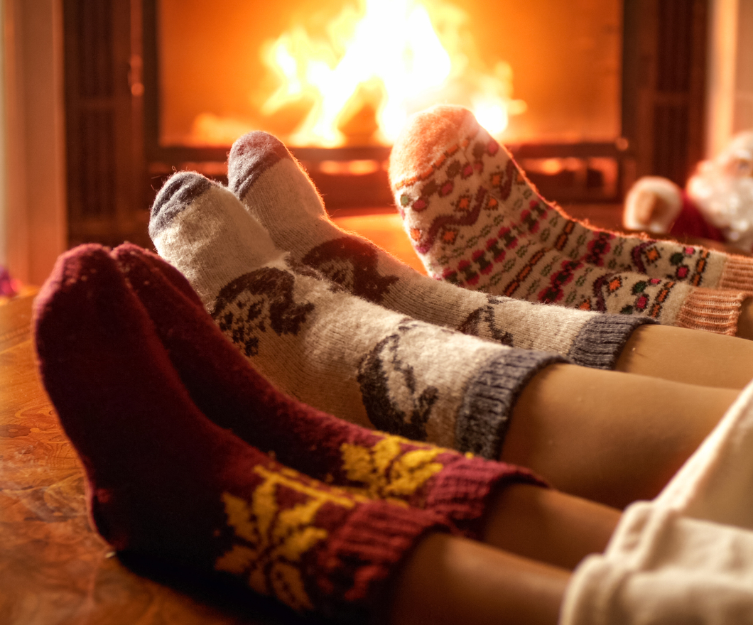 Closeup image of family feet in woolen socks lying next to fireplace